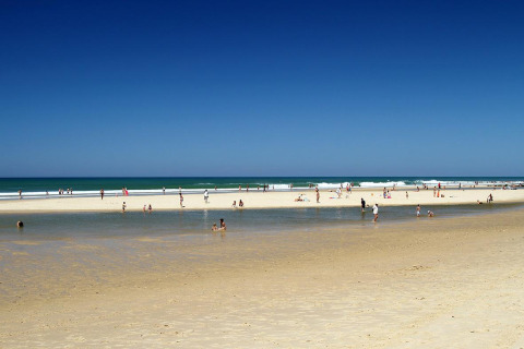 Playa cerca de Carcans, Nouvelle-Aquitania, Francia, con personas disfrutando el sol, la arena y el agua.