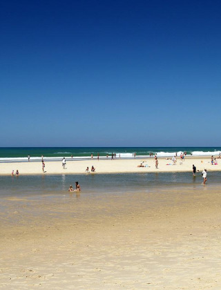 Strand in der Nähe von Carcans, Nouvelle-Aquitaine, Frankreich, mit Menschen, die Sonne und Meer genießen.