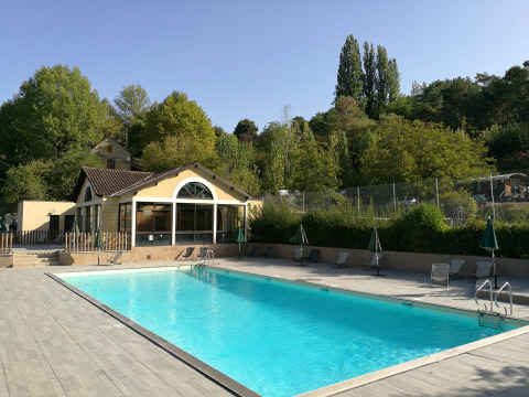 Piscina al aire libre en Huttopia Sarlat, un parque vacacional en Nouvelle-Aquitaine, Francia, rodeada de árboles.
