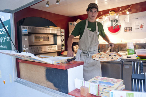 Un pizzaiolo in un food truck prepara pizze per gli ospiti di Huttopia Sarlat in Nouvelle-Aquitaine, Francia.