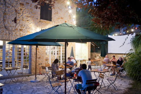 Zona de comedor al aire libre en Huttopia Sarlat, parque vacacional en Nouvelle-Aquitaine, Francia, de noche.