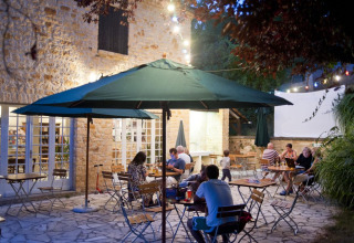 Udendørs spiseområde hos Huttopia Sarlat feriepark i Nouvelle-Aquitaine, Frankrig, belyst om aftenen.