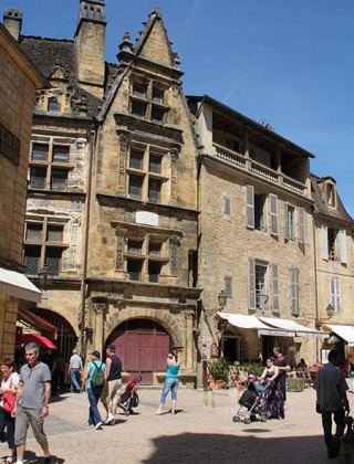 Personas pasean por una pintoresca plaza rodeada de edificios antiguos en Sarlat la Caneda, Nouvelle-Aquitaine, Francia.