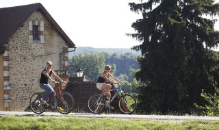 Dos mujeres en bicicleta pedalean por un camino rural cerca de Sarlat la Caneda, Nouvelle-Aquitania, Francia.