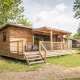 Træhytte ved navn Chalet Portland med veranda i solrigt skovområde, omgivet af grønne træer og græs.