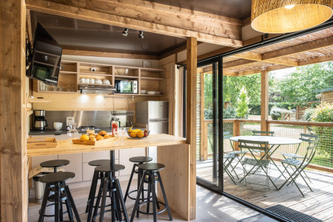 Lyst køkken og spiseområde i Chalet Portland, åbner ud til en terrasse med udsigt til grøn natur.