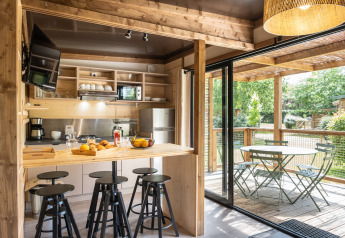 Lyst køkken og spiseområde i Chalet Portland, åbner ud til en terrasse med udsigt til grøn natur.