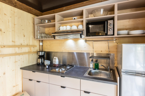 Moderne køkken i Chalet Portland med træpaneler, gaskomfur, vask, mikroovn og åbne hylder.