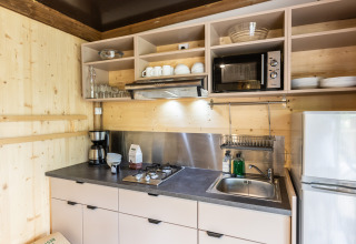 Cocina moderna en Chalet Portland con paredes de madera, cocina a gas, fregadero, microondas y estantes.
