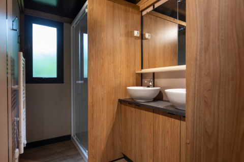 Baño moderno en Chalet Ottawa con paneles de madera, dos lavabos tipo cuenco y ducha acristalada.