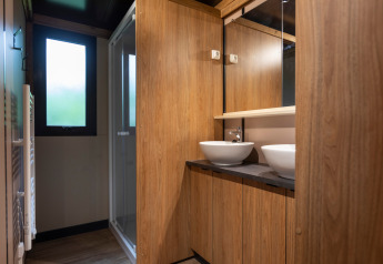 Moderne badkamer in Chalet Ottawa met houten wandbekleding, dubbele waskommen en glazen douchecabine.