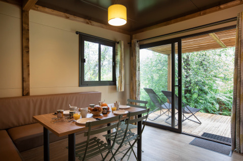 Innenansicht des Chalet Ottawa mit Esstisch, Stühlen, großem Fenster und Terrasse mit Gartenblick.