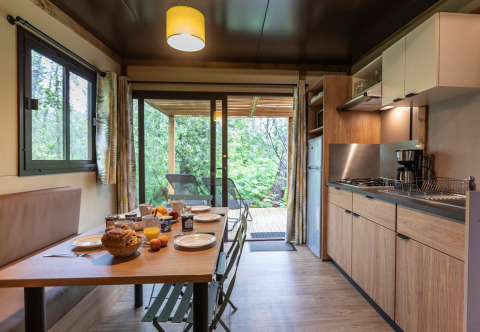 Cocina moderna y comedor en Chalet Ottawa, desayuno preparado en la mesa, vista al bosque desde la terraza.