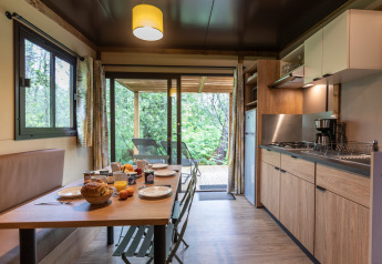 Moderne køkken og spiseplads i Chalet Ottawa med udsigt til skov fra terrasse, morgenmad på bordet.