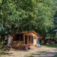 Tienda safari Arizona en un camping arbolado, rodeada de árboles verdes y sillas para relajarse afuera.