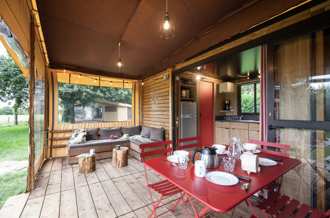 Safari-Zelt Arizona mit gemütlicher Terrasse, Esstisch, Lounge-Bereich und Blick ins Grüne.