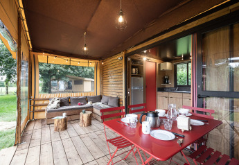 Safari-Zelt Arizona mit gemütlicher Terrasse, Esstisch, Lounge-Bereich und Blick ins Grüne.