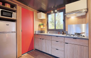Cocina moderna de tienda safari Arizona con gabinetes de madera, estufa a gas, refrigerador y ventana.