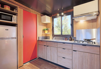 Cocina moderna de tienda safari Arizona con gabinetes de madera, estufa a gas, refrigerador y ventana.