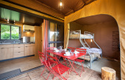 Tienda safari Arizona con cocina moderna, litera y comedor rojo sobre suelo de madera, vista interior.