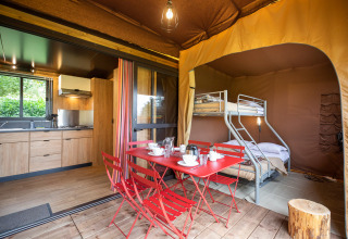Tienda safari Arizona con cocina moderna, litera y comedor rojo sobre suelo de madera, vista interior.