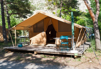 Tente safari Trappeur sur terrasse en bois à Huttopia Gorges du Verdon, France, entourée d’arbres verts.