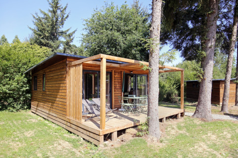 Træhytte med terrasse og havemøbler omgivet af træer i naturlige omgivelser ved Chalet Ottawa.