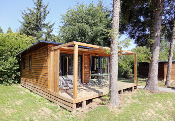 Træhytte med terrasse og havemøbler omgivet af træer i naturlige omgivelser ved Chalet Ottawa.