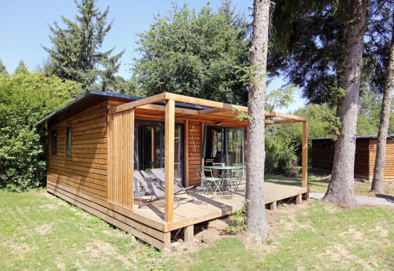 Træhytte med terrasse og havemøbler omgivet af træer i naturlige omgivelser ved Chalet Ottawa.