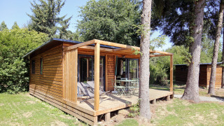 Gemütliche Holzchalet mit Terrasse und Gartenmöbeln, umgeben von Bäumen bei Chalet Ottawa.