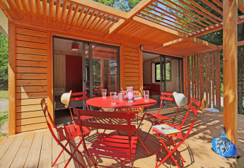 Terraza en Chalet Ottawa, Huttopia Baie du Mont St Michel, Francia, con sillas rojas y pérgola de madera.
