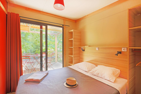 Dormitorio en Chalet Ottawa de Huttopia Baie du Mont St Michel, Francia, con vista a la terraza exterior.