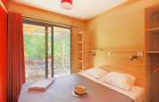 Dormitorio en Chalet Ottawa de Huttopia Baie du Mont St Michel, Francia, con vista a la terraza exterior.