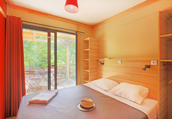 Dormitorio en Chalet Ottawa de Huttopia Baie du Mont St Michel, Francia, con vista a la terraza exterior.