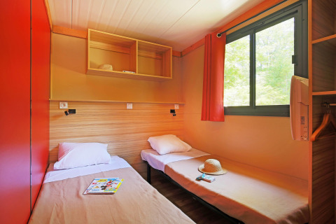 Dos camas individuales en una habitación luminosa con ventana en Chalet Ottawa, Huttopia Baie du Mont St Michel, Francia.