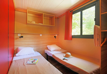 Dos camas individuales en una habitación luminosa con ventana en Chalet Ottawa, Huttopia Baie du Mont St Michel, Francia.