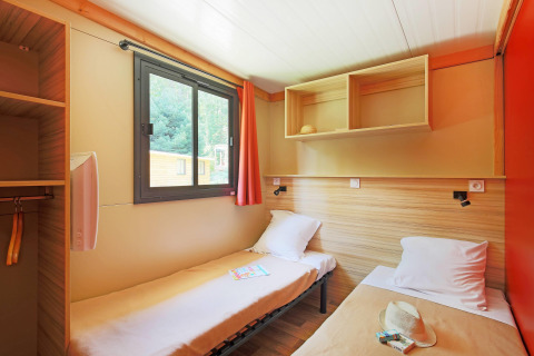Acogedora habitación doble con ventana y estanterías en Chalet Ottawa, Huttopia Baie du Mont St Michel, Francia.