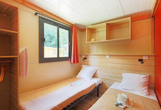 Acogedora habitación doble con ventana y estanterías en Chalet Ottawa, Huttopia Baie du Mont St Michel, Francia.