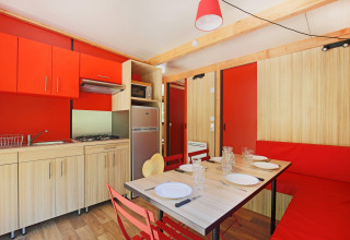 Cocina y comedor modernos en Chalet Ottawa de Huttopia Baie du Mont St Michel con detalles en rojo y madera.