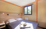 Dormitorio luminoso en Mobile home Vancouver de Huttopia Baie du Mont St Michel, con cama doble y ventana.