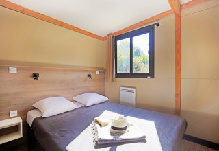 Chambre lumineuse du Mobile home Vancouver à Huttopia Baie du Mont St Michel, avec lit double et fenêtre.