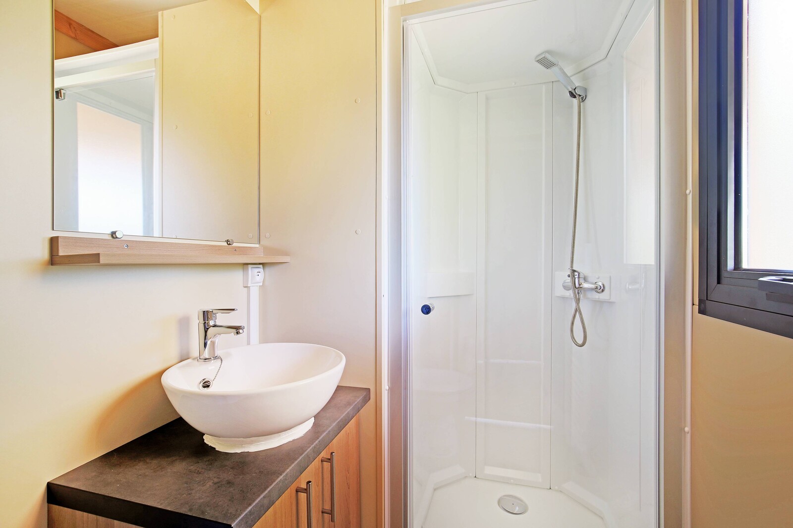 Moderne badkamer met wastafel, spiegel en douche in Mobile home Vancouver, Huttopia Baie du Mont St Michel, Frankrijk.