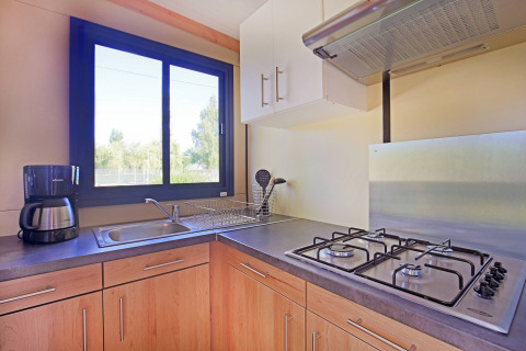 Moderna cucina di cabina con fornello a gas, lavello, macchina da caffè e finestra a Huttopia Baie du Mont St Michel.