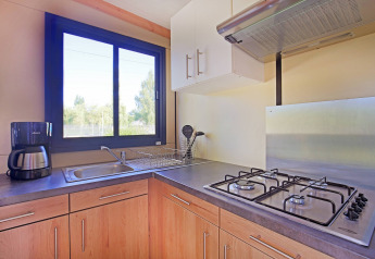 Moderna cucina di cabina con fornello a gas, lavello, macchina da caffè e finestra a Huttopia Baie du Mont St Michel.