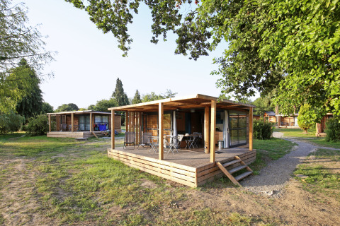 Chalet Evasion ved Huttopia Baie du Mont St Michel i Frankrig, omgivet af grønne træer og natur.