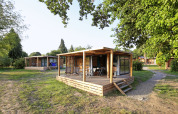 Chalet Evasion ved Huttopia Baie du Mont St Michel i Frankrig, omgivet af grønne træer og natur.