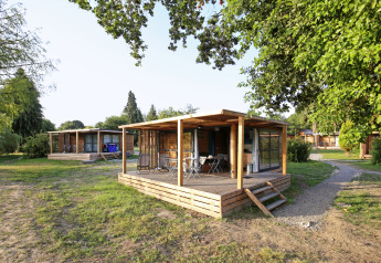 Chalet Evasion ved Huttopia Baie du Mont St Michel i Frankrig, omgivet af grønne træer og natur.