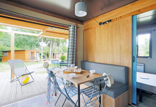 Vista interior de un chalet acogedor en Huttopia Baie du Mont St Michel, con terraza y cabañas afuera.