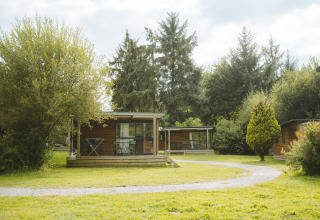 Chalet Evasion en Huttopia Baie du Mont St Michel, Francia, rodeado de árboles y un paisaje verde y natural.