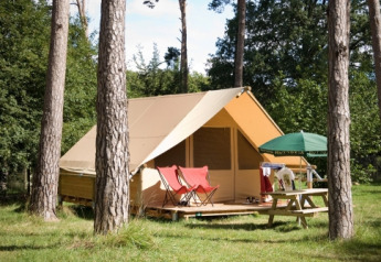 Tienda safari Canadienne en Huttopia Rambouillet, Francia, rodeada de árboles y zona de picnic exterior.